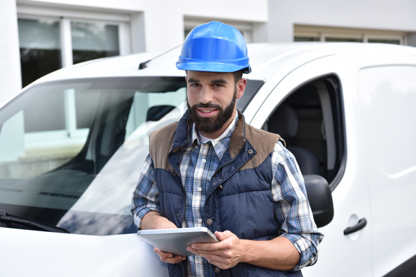 Contractor leaning on white van with a tablet